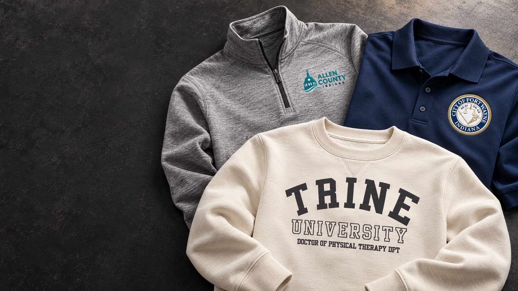 A Trine University crewneck displayed with embroidered Allen County and City of Fort Wayne apparel